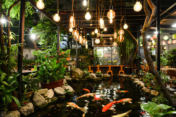 Restaurant with a large fish tank and many lights. The restaurant has a lot of tables and chairs, and there are several people sitting and eating. The atmosphere is lively and inviting