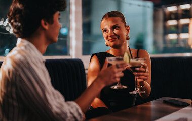 A young couple shares a special moment at a stylish bar, enjoying cocktails on a night out. The atmosphere is intimate and lively, perfect for socializing and relaxation.