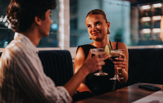A young couple shares a special moment at a stylish bar, enjoying cocktails on a night out. The atmosphere is intimate and lively, perfect for socializing and relaxation.