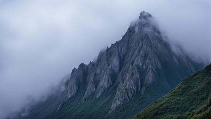 A majestic mountain peak shrouded in mist, showcasing rugged terrain and natural beauty.