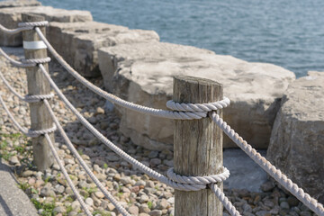rope fence barrier break water stones and lake