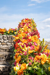 Colorful flower arrangement with lilies and roses with old stone walls in the background