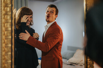 A joyful couple laughing and preparing for an exciting night out. The man wears a stylish suit while the woman appears delighted.
