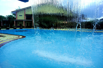 A fountain designed to resemble a waterfall, serving as a decorative feature for a family swimming pool