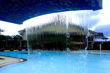 A fountain designed to resemble a waterfall, serving as a decorative feature for a family swimming pool