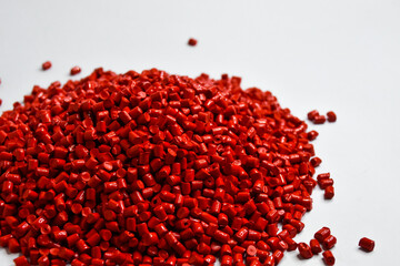 Red masterbatch granules on a white background, a color pigment carrier polymer in the plastics industry