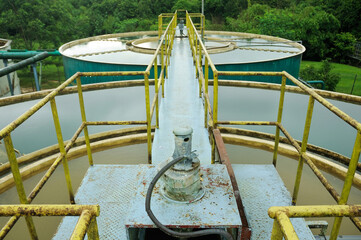a water treatment facility featuring several large storage tanks filled with water. Surrounding the tanks are large green pipes, likely used to transfer water between the tanks