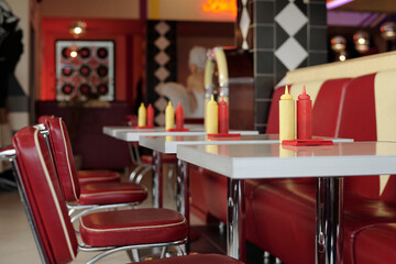 Retro-style diner with classic red and yellow dining booth, condiment bottles, and vintage decor...