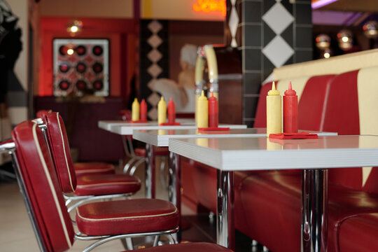 Retro-style diner with classic red and yellow dining booth, condiment bottles, and vintage decor creating nostalgic ambiance reminiscent of mid-20th century American diners