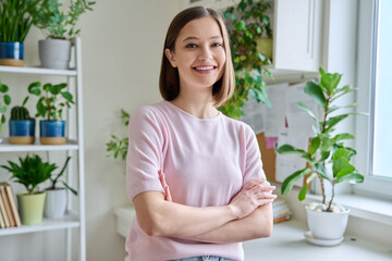 Portrait of young confident smiling woman in home interior