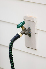 Outdoor water spout with green and black hose attached