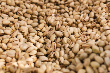 Pile of pistachios snack. Nutty texture background. Group of fresh pistachio nuts stacked in a heap. Delicious, crunchy snack for healthy eating.