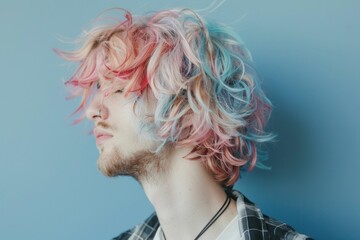 Colorful hairstyle, pastel colors, modern look, artistic portrait of a young man with wavy hair, blue and pink hues, side profile against a soft blue background, creative style