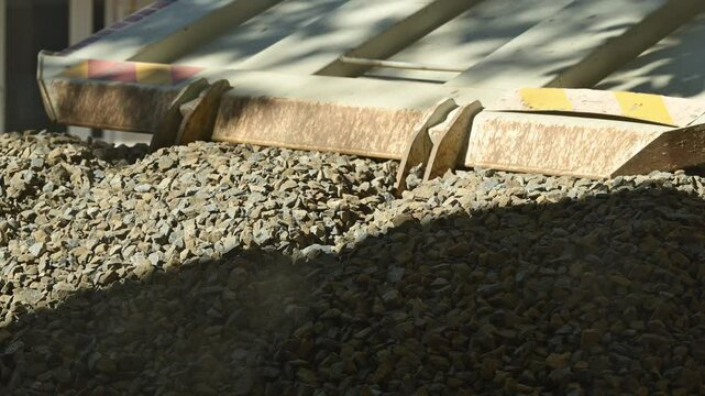 Truck unloading crushed stone gravel on construction site, slow motion 4K