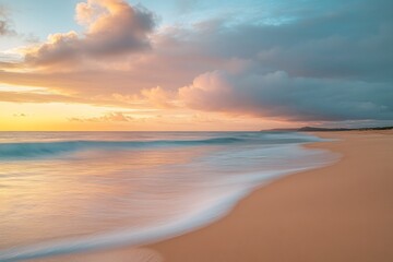 Obraz premium Serene beach at sunset with pastel clouds and gentle waves on golden sand, capturing tranquil atmosphere in high-resolution detail.