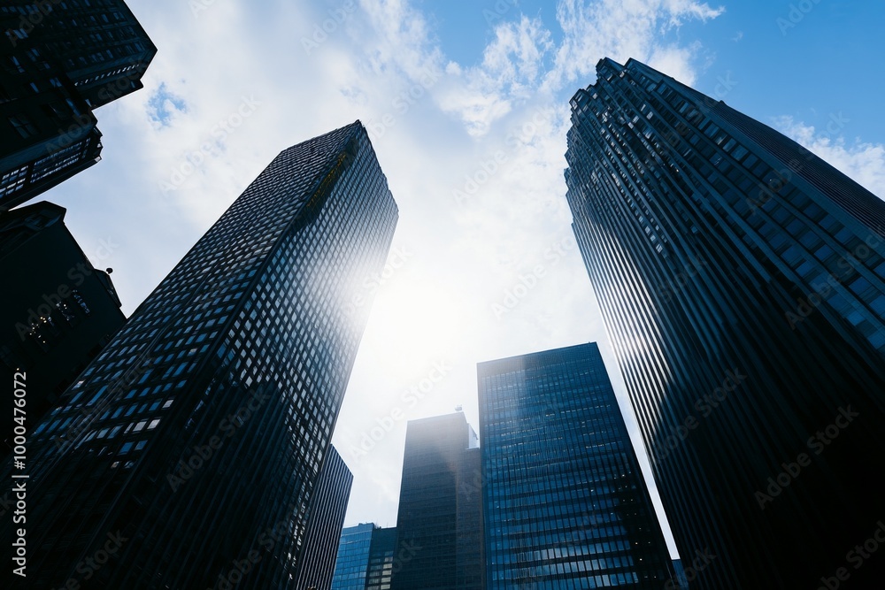 Wall mural cinematic skyscape-style view of tall buildings in a city under daylight, featuring sunlight, shadow