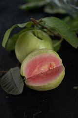 Pink and green guava slice with leaf on dark table