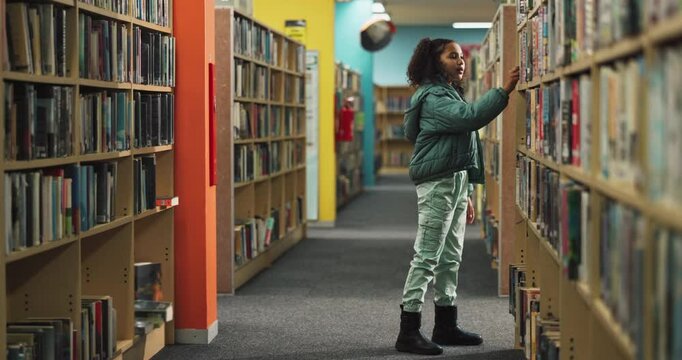 Girl, walking and library with bookshelf for knowledge, story or learning literature at bookstore. Young female person or student looking for reading novel, story or information by bookcase at shop