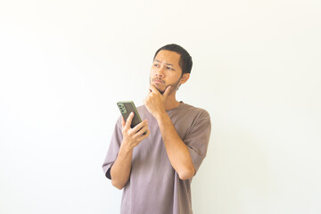 Pensive young asian men is thinking while holding smathphone on isolated white background