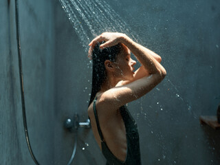Woman in the shower feeling overwhelmed as water runs down her body with hands on head