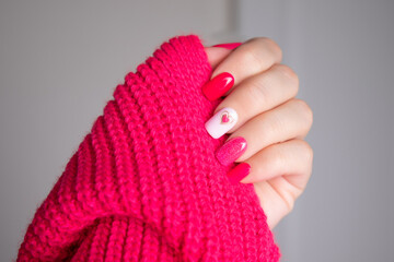 Beautiful female hand with pink manicure nails, heart and Valentine's day design