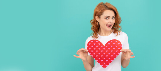 cheerful redhead lady hold red heart on blue background. Woman isolated face portrait, banner with mock up copyspace.