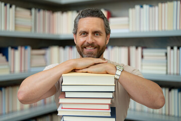 Teachers day. Funny teacher hold many books. Crazy teacher with books. Excited teacher in school book library. Teacher from university exam. College teachers.