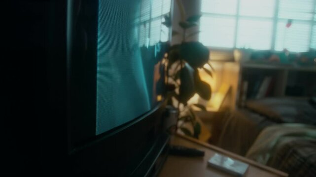 Side closeup of hand of anonymous person inserting video cassette into video tape recorder and watching horror movie on tube tv at home in 90s