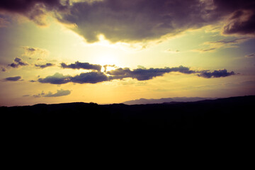 Silhouette of a person watching the sunset over the mountains, adding a contemplative mood to the scene. The vibrant colors of the sky create a stunning contrast.