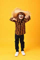 Funny boy dressed like scarecrow on yellow background. Halloween celebration