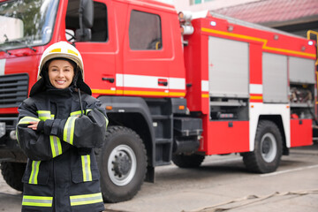 Obraz premium Portrait of firefighter in uniform and helmet near fire truck outdoors
