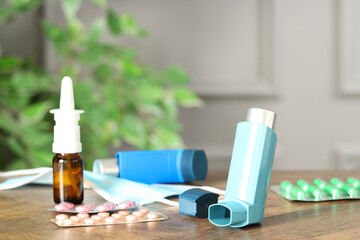 Different asthma medications on wooden table indoors, closeup