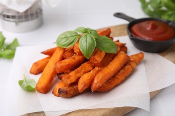 Sweet potato fries, basil and ketchup on white table, closeup