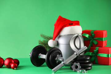 Dumbbells, container with supplement and Christmas decor on green background. Space for text