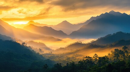Obraz premium Golden sky at sunrise with mist rolling over a mountain range, offering a serene and peaceful nature scene