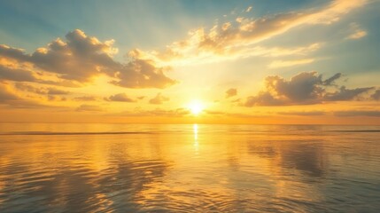 Fototapeta premium Golden sky at sunrise with soft clouds and reflections on the ocean, creating a serene and picturesque scene