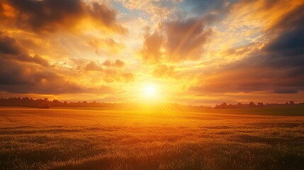 Obraz premium Golden sky with sun rays piercing through clouds at sunset, casting a glowing light over a quiet countryside -