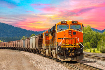 freight train pulling cargo with a beautiful sunset in the background close to Whitefish, Montana