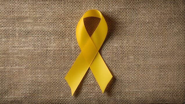 Yellow ribbon on textile background with copy space for endometriosis awareness month or sign for microencephaly and suicide prevention