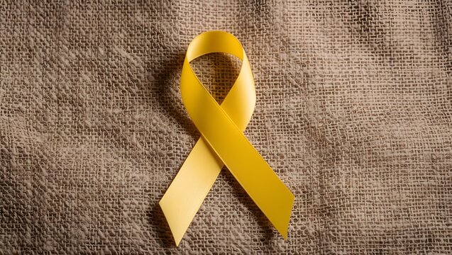 Yellow ribbon on textile background with copy space for endometriosis awareness month or sign for microencephaly and suicide prevention
