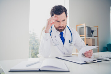 Photo of pensive doctor guy read check list medical service in white hospital room