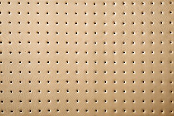 Beige perforated material with regular pattern of small holes close-up