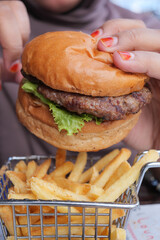 hand holding beef burger on table close up 