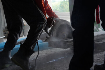 A builder using a circular saw to cut a large concrete piece