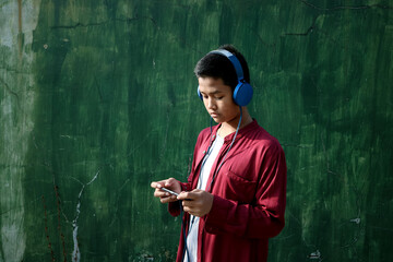 A teenager who is using their headphones and cellphone.