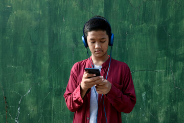 Fototapeta premium A teenager who is using their headphones and cellphone.