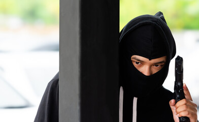 Dangerous Thief wearing black robe's hat is using a gun.