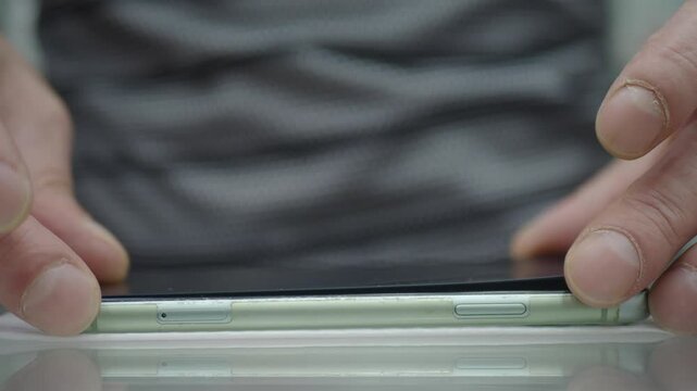 A pair of hands meticulously inspecting a smartphone screen to ensure complete flatness and quality