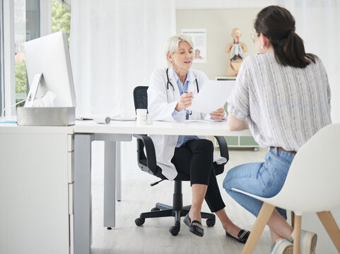 Women, doctor and patient with documents for results at office on consultation for diagnosis. Hospital, medical profession and discussion or meeting with paperwork for guidelines or rules on surgery