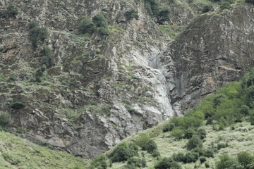 A rugged black stone formation on a barren mountainside, devoid of trees or vegetation.